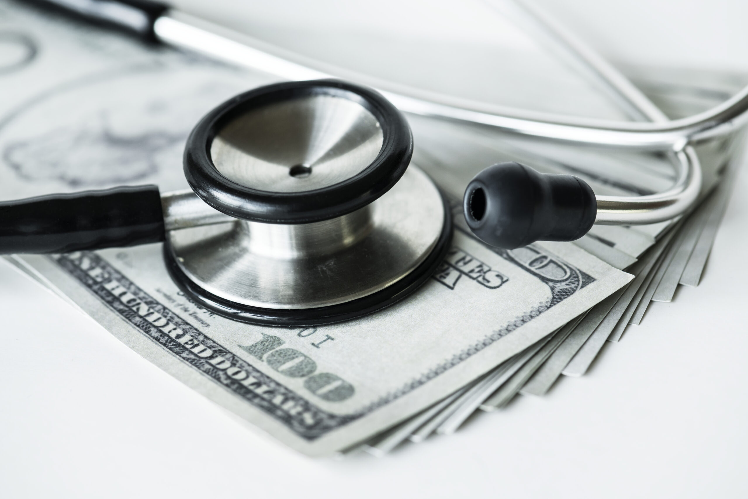 closeup cash stethoscope healthcare expenses concept scaled